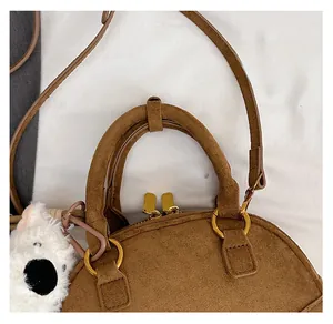 Detail view of brown suede bowling bag with golden rings and cute white dog charm