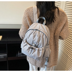 Detail of grey lightweight nylon backpack featuring dual zippers and front drawstring pocket