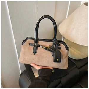 Détail d'un sac cabas en daim marron avec bordures en cuir noir et boucles dorées