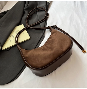 Detail view of dark brown crescent bag showing suede texture and smooth leather contrast