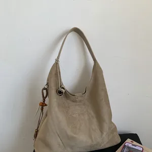 Dettaglio della borsa tote in finta pelle scamosciata kaki con ciondolo etnico in legno