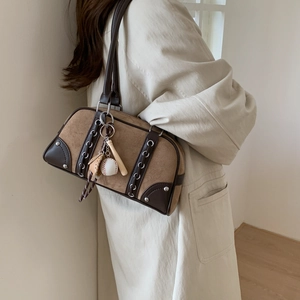 Close-up of brown suede Boston bag with leather trim and creative baseball charm detail