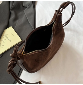 Detail view of suede dumpling bag with woven knot handle and textured leather stitching