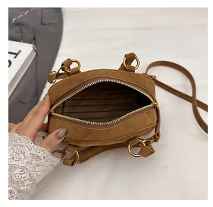Interior view of brown suede handbag showing striped lining and metal hardware detail