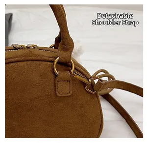 Close-up of golden metal ring hardware and detachable shoulder strap on brown suede handbag