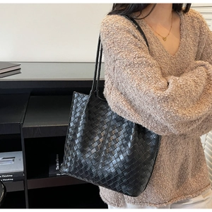 Close-up of black woven tote bag showing the intricate intrecciato leather texture