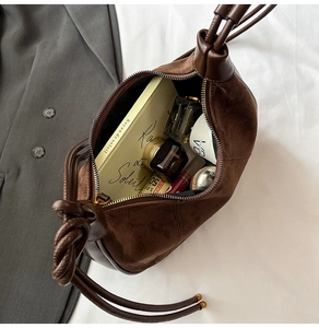 Detail of suede crossbody bag showing interior capacity with essentials on fabric