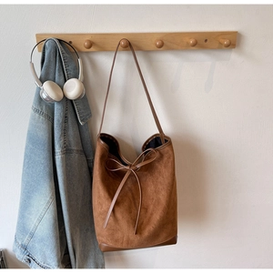 Détail du sac cabas en daim marron avec nœud décoratif et coins en cuir renforcés