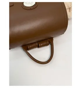 Detail of durable brown leather handle and circular logo on the commuter backpack