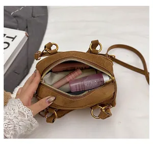 Brown suede bowling bag interior showing capacity for cosmetics with bronze metal handles