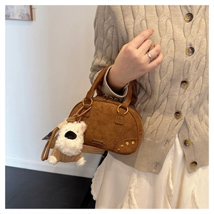 Detail of vintage brown suede bowling bag with a cute plush dog charm and gold rivets