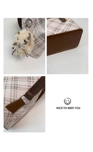 Detailed close-up of checkered canvas bag with plush bunny charm and brown leather base