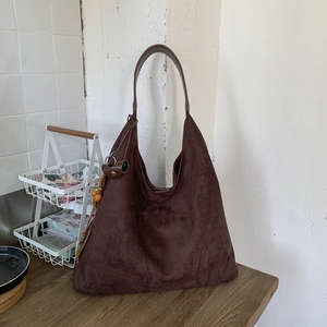 Dettaglio della borsa tote in pelle scamosciata marrone scuro con decorazione laterale in legno