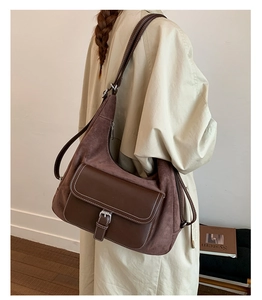 Close-up of matte brown leather shoulder bag with white stitching and silver buckle detail