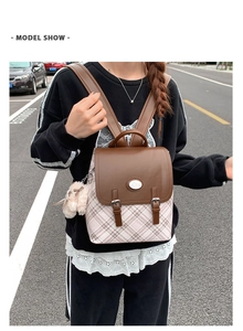 Detail of vintage plaid backpack with brown faux leather flap and plush charm on the strap