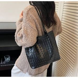 Detail of black woven leather tote bag showing the Intrecciato pattern and slim straps