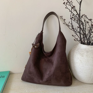 Vista dettagliata della borsa tote grande in camoscio marrone con ciondolo in legno e magnete