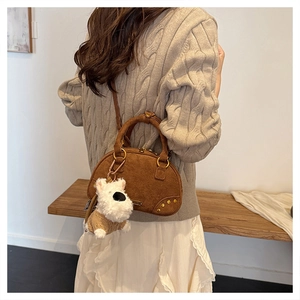 Detailed back view of model wearing a brown suede bowling bag with a white plush puppy charm