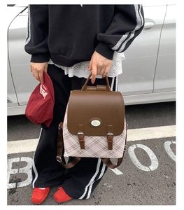 Detail of pink plaid fabric and brown leather flap with rabbit logo on a vintage backpack