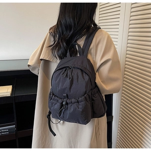 Side view of a minimalist black nylon backpack worn by a model for daily commuting use