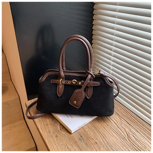 Détail du tissu givré noir et de la poignée en cuir marron sur un sac vintage élégant