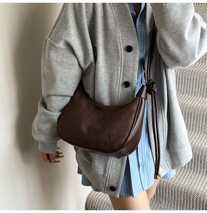 Detail view of dark brown crescent bag with suede patchwork and decorative knot strap