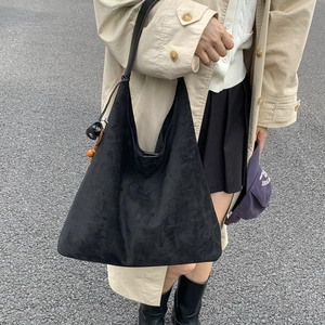 Dettaglio di una grande borsa tote in pelle scamosciata nera con ciondolo decorativo in perle