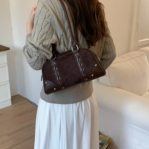 Detail view of retro brown suede patchwork shoulder bag with decorative metal ring buckles