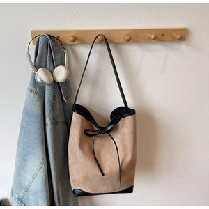 Détail du grand sac cabas en daim avec garnitures en cuir noir et nœud décoratif élégant