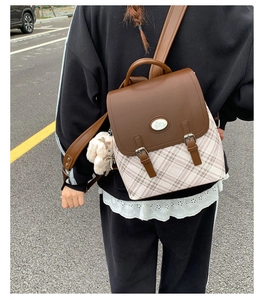 Detail of vintage plaid backpack with brown leather flap and cute plush bunny charm