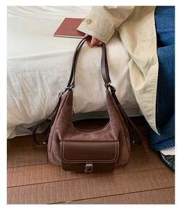 Detailed view of brown frosted leather tote bag featuring white contrast stitching and clasp