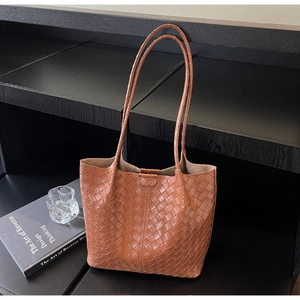Close-up of brown woven leather tote bag with classic chevron texture and slim straps