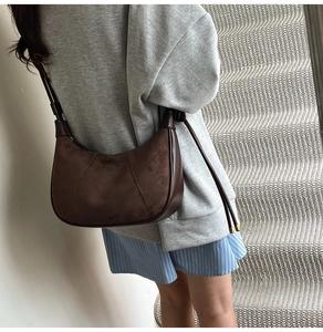 Detailed shot of dark brown suede crescent bag with elegant diagonal stitching details