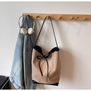 Détail du sac cabas en daim camel avec bordure en cuir noir et nœud décoratif