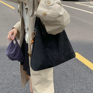 Dettaglio della borsa tote in camoscio nero con chiusura a coulisse e nappa con perline