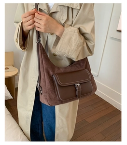 Detail of vintage brown suede dumpling bag with white contrast stitching and metallic buckle