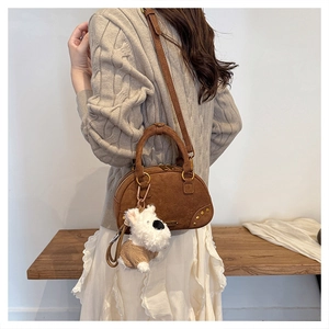 Detail of dark brown suede handbag with golden rivets and cute plush dog pendant charm