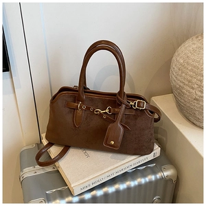 Détails d'un sac à main en daim marron foncé sur une valise argentée au style rétro