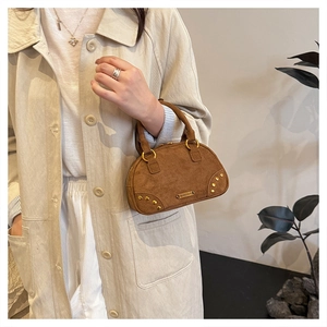 Brown faux suede bowling bag featuring metallic rivets and a vintage crossbody design