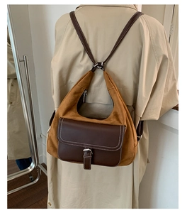 Detail of vintage caramel suede dumpling bag worn over a beige trench coat