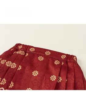 Close-up of red pleated skirt with golden plum blossom jacquard and silk texture