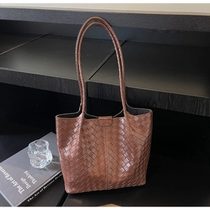 Detailed view of brown woven leather texture on a large capacity tote bag with long straps