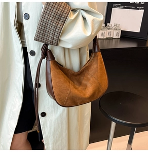 Detailed view of brown suede crescent bag with braided strap and smooth leather trim
