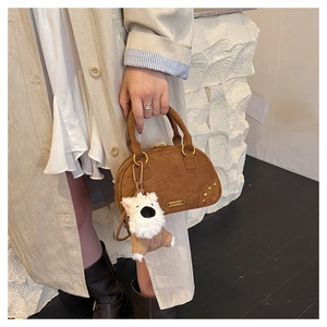 Brown faux suede bowling bag with golden ring handles and a white plush puppy charm