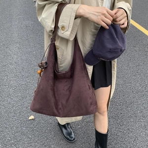 Dettaglio della borsa tote in pelle scamosciata marrone con manici in pelle e ciondolo in legno