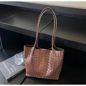 Detailed close-up of woven dark brown leather texture on a stylish tote bag