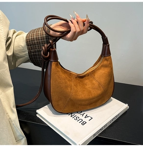Detailed macro view of the brown suede crescent bag with premium smooth leather handles