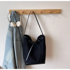 Vue détaillée du sac cabas noir avec décoration en nœud et bordure en cuir sur un crochet