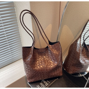 Close-up of brown leather woven tote bag showing luxury texture and long shoulder straps
