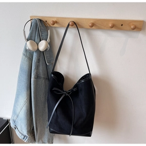 Détail du sac cabas en toile noire avec nœud en cuir et bordures de renforcement